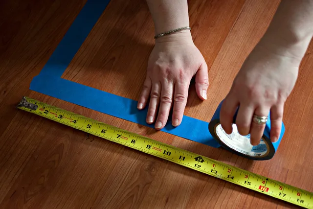Taping off a section of hardwood floor with blue tape and yellow measuring tape (16147275678). Accessible Laundry Room Floor Space and Door Swings: A 2027 Measuring Guide